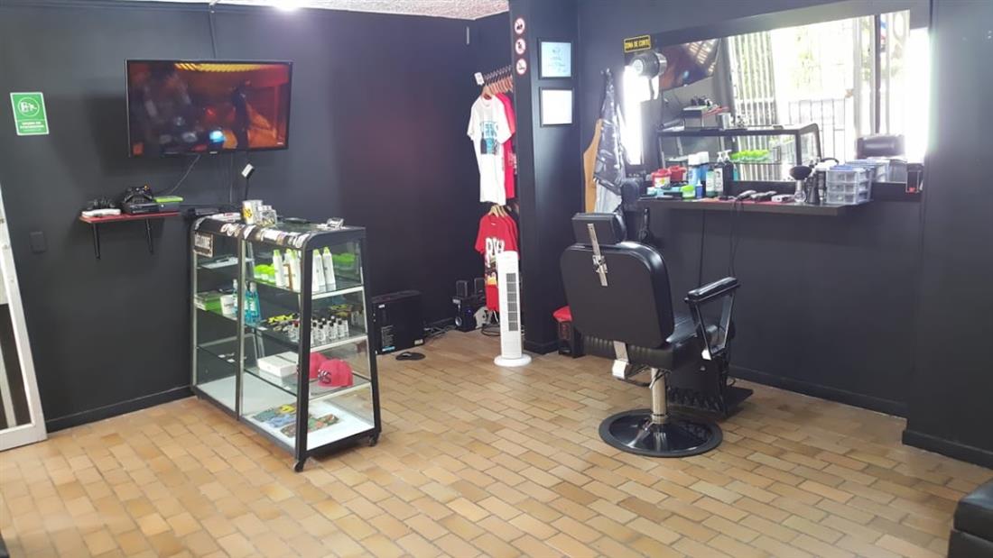 Interior de Represent: vitrina con productos, camisetas colgadas y gorras, silla de barbero negra